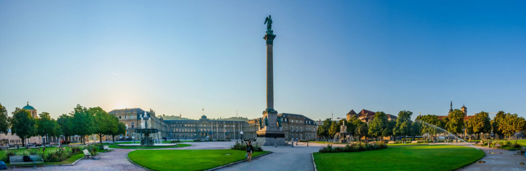 Foto für die Standortseite "Schuldnerberatung Schulz in Stuttgart". Das Foto zeigt den Schlossplatz in Stuttgart. Im Zentrum steht die Jubiläumssäule mit der Concordia-Statue, flankiert von Brunnen und umgeben von historischen Gebäuden wie dem Neuen Schloss. Die gepflegte Parkanlage lädt zum Verweilen ein und ist ein zentraler Ort im Herzen der Stadt.
