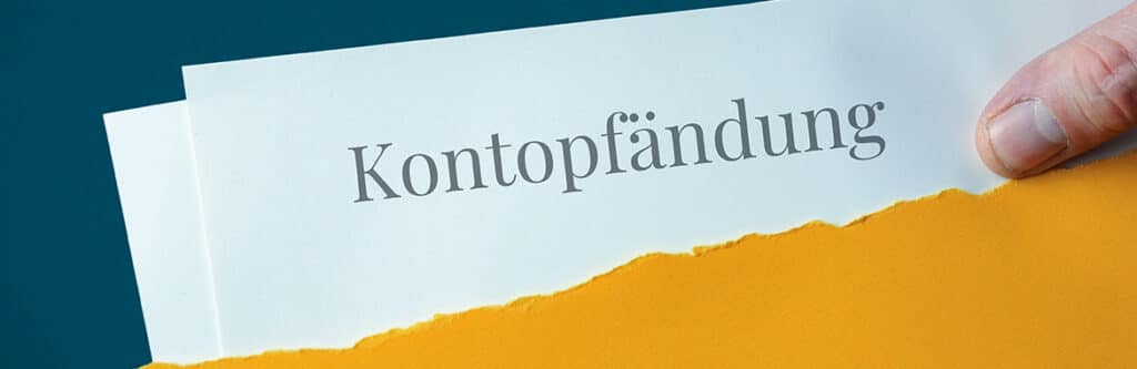 Foto für den Blogartikel "Ablauf einer Kontopfändung". Man sieht ein Schriftstück mit dem Wort "Kontopfändung" in großer, klarer Schrift. Das Dokument steckt in einem gelben Umschlag, der am unteren Rand aufgerissen ist. Rechts oben ist eine Hand zu sehen, die das Schreiben festhält und ein Stück herauszieht. Das Bild vermittelt den Eindruck eines amtlichen und sehr ernsten Schreibens.