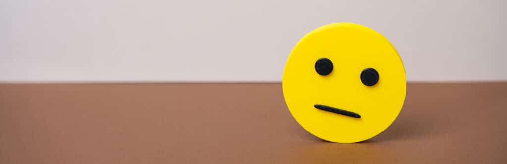 Foto für den Blogartikel "Schuldenbarometer 2025: Deutlich mehr Privatinsolvenzen". Auf dem Foto sieht man ein gelbes neutrales Smiley-Gesicht auf brauner Fläche vor hellem Hintergrund, das die eher verhaltene Stimmung im Schuldenbarometer 2025 symbolisiert.