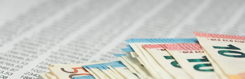 Foto für den Blogartikel "Pfändungstabelle 2026 / 2027: Pfändungsfreigrenzen ab 1. Juli 2026". Auf dem Foto sieht man einen Stapel von Euro-Banknoten auf einer Tabelle mit Zahlenkolonnen – symbolisch für die Pfändungstabelle.