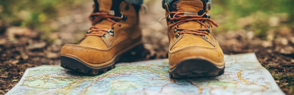 Foto für den Blogartikel "Privatinsolvenz ohne festen Wohnsitz - ist das möglich?". Auf dem Foto sieht man Wanderschuhe auf einer ausgebreiteten Landkarte im Freien stehen – symbolisch für die Option einer Privatinsolvenz ohne festen Wohnsitz und das Leben unterwegs.