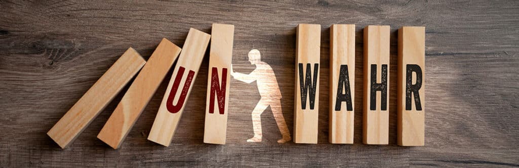 Foto für den Blogartikel "Eidesstattliche Erklärung: Was müssen Privatpersonen beachten?". Auf dem Foto sieht man Holzklötze mit den Wörtern "UN" und "WAHR" sowie eine Figur dazwischen – symbolisch für die Bedeutung der eidestattlichen Erklärung zwischen Wahrheit und Falschangaben.