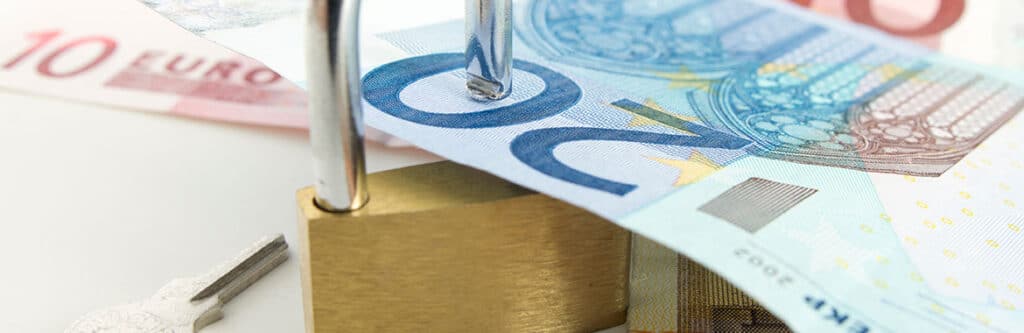 Foto für den Blogartikel "PSK-Auskehrungskonto - alle wichtigen Infos". Auf dem Foto sieht man ein Vorhängeschloss mit Schlüssel auf Euro-Banknoten liegen – symbolisch für gesperrtes Guthaben und finanzielle Verwaltung beim PSK-Auskehrungskonto.